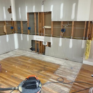 Room under renovation with exposed wiring and wooden floor.