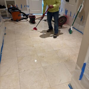 Worker mopping tiled floor in hallway