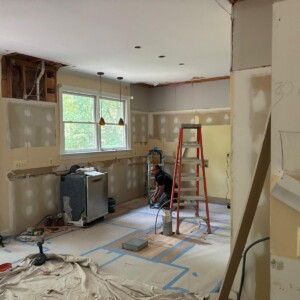 Room under renovation with construction tools and a worker preparing the floor.