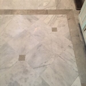 Marble floor with gray border and small square inserts.