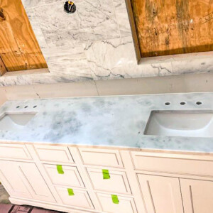 Double sink vanity with white marble countertop during bathroom installation.