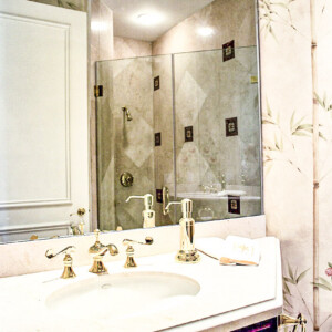 Elegant bathroom sink with gold fixtures and a decorative mirror.