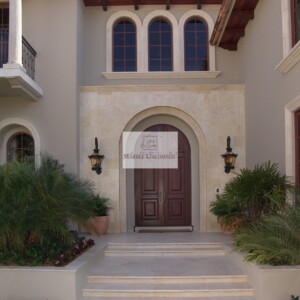 Elegant entrance with arched doorway and lush greenery.