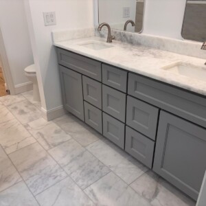 Modern bathroom with gray vanity and marble flooring.
