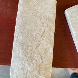 Close-up of a textured stone slab with faint engraved markings on a wooden surface.