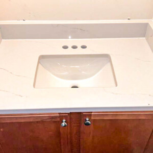 White marble bathroom sink countertop with brown cabinet.
