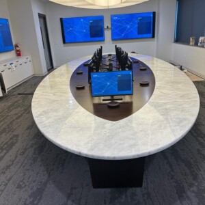 Modern conference room with a unique oval table and multiple monitors.
