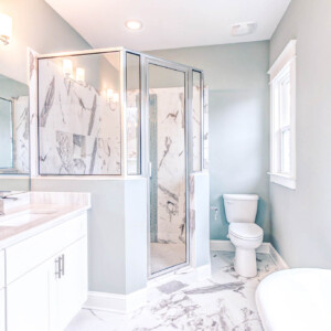 Modern bathroom with marble accents and glass shower enclosure.