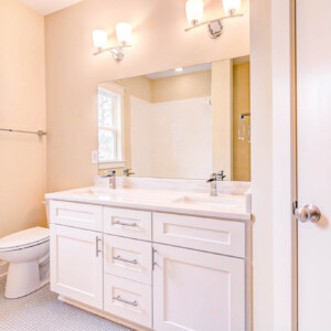 Clean, modern bathroom with white vanity, dual sinks, and beige walls.