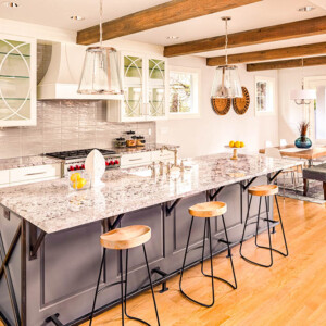 Modern kitchen with a large granite island and wooden stools.
