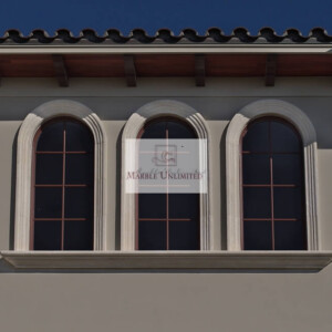 Three arched windows with decorative stone frames on a beige wall under a tiled roof.
