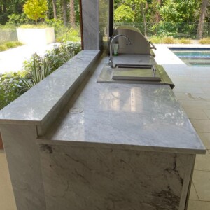 Sleek outdoor kitchen with marble countertops and built-in grill.