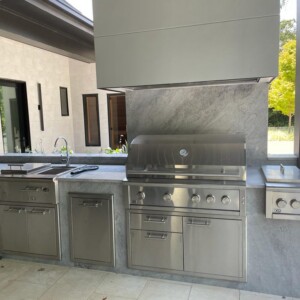 Modern outdoor kitchen with stainless steel appliances and marble countertops.