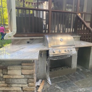 Outdoor stone grill setup with a stainless steel barbecue and marble countertop.